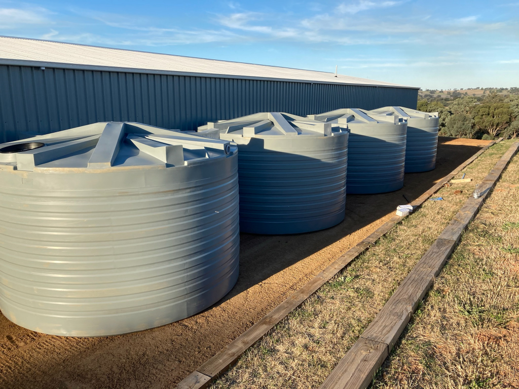 Four large round water tanks in a rural setting